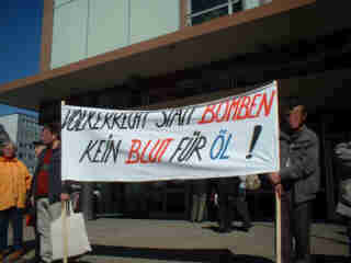 Foto: Demonstrierende und Passanten. Transparent: "Völkerrecht statt Bomben Kein Blut für Öl"