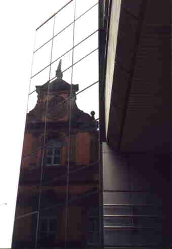 Die Fassade eins alten Hauses spiegelt sich in der Glasfassade eines modernen Gebäudes...