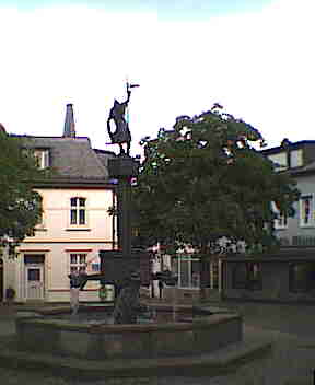 Ein Brunnen auf einem Platz in der Altstadt. Mit Bronzetafeln, auf denen Geschichtsszenen abgebildet sind.